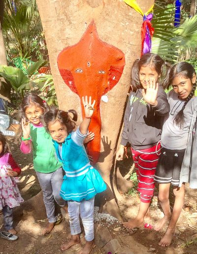 A flamboyant tree with a natural Ganesha on the trunk and Children from the neighbourhood in Jungle Garden